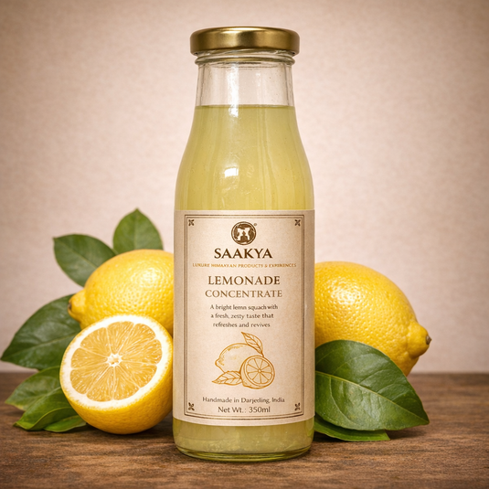 Glass bottle of Saakya Lemonade Concentrate with lemons on a wooden surface