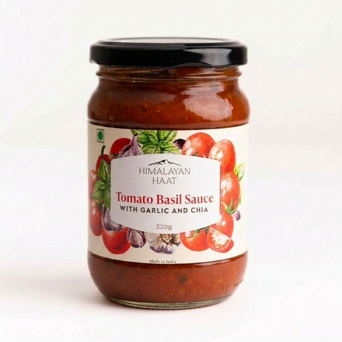 A glass jar of Himalayan Haat Tomato Basil Sauce with Garlic and Chia, featuring a white label with red tomatoes and green basil illustrations, topped with a black lid on a white background.